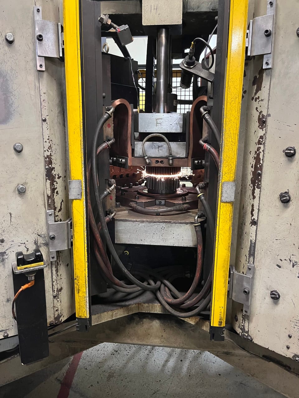 A PECo capacitor discharge welder producing sparks between yellow safety guards