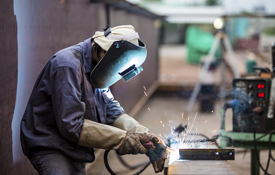 Welder using a torch on a metal pipe
